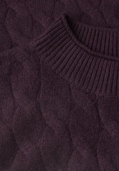 Gros plan sur un pull en maille torsadée violet foncé à col rond côtelé.