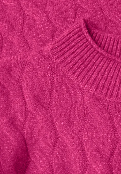 Close-up van een roze gebreide trui met vlechtpatroon