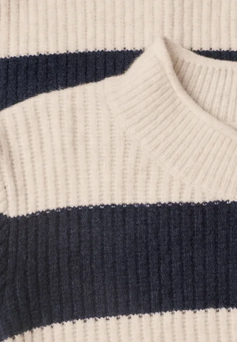 Gros plan sur un pull en maille à larges rayures crème et bleu marine.