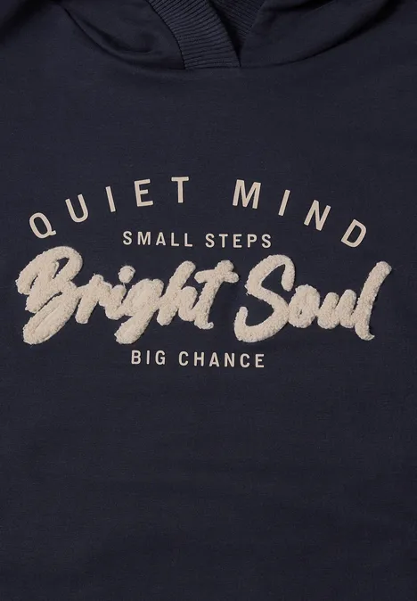 Dunkelblauer Pullover mit hellbeigeem Schriftzug 'Quiet Mind Small Steps Bright Soul Big Chance'.
