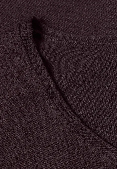 Tissu fin noir avec couture apparente formant un col rond.