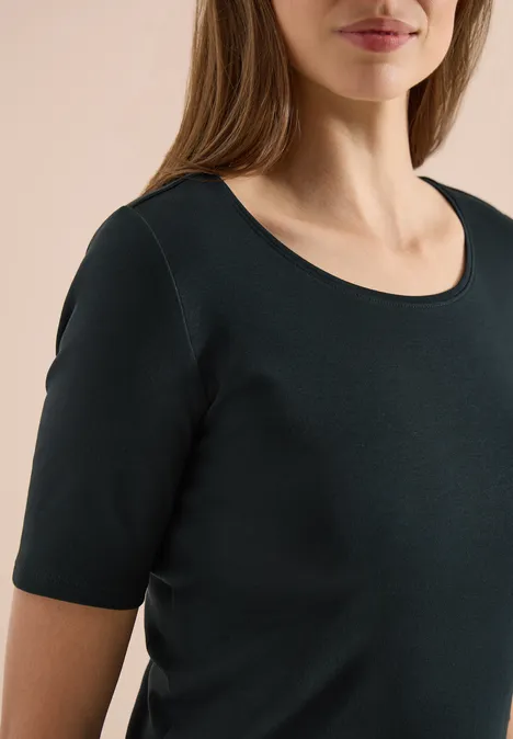 Femme portant un t-shirt noir uni à manches courtes et col rond.