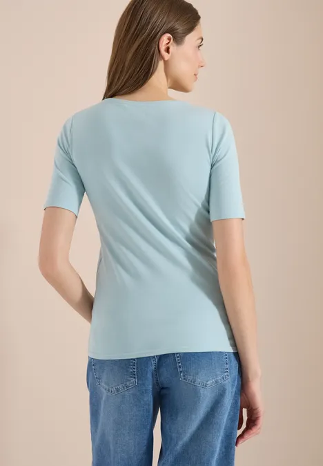 Vrouw van achteren in een lichtblauw shirt en spijkerbroek.