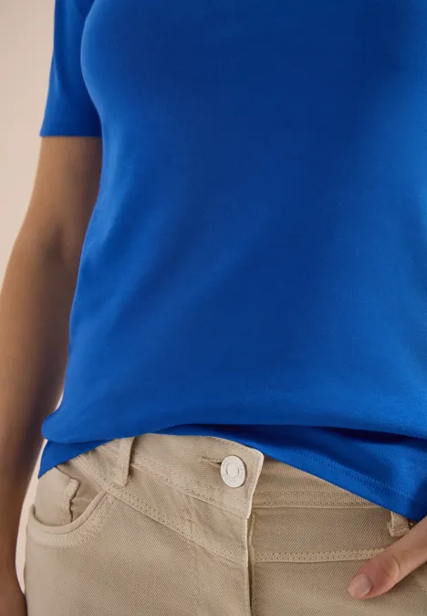 Blauw bovenstuk en beige broek in close-up van torso tot taille.