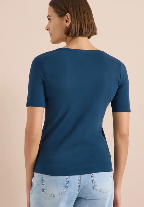 Rückenansicht einer Person mit dunkelblauem T-Shirt und hellblauen Jeans.