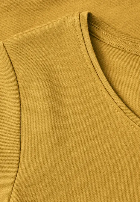 Basic T-shirt met ronde hals golden honey Nahaufnahme eines ockerfarbenen T-Shirt-Ausschnitts und -Ärmels.