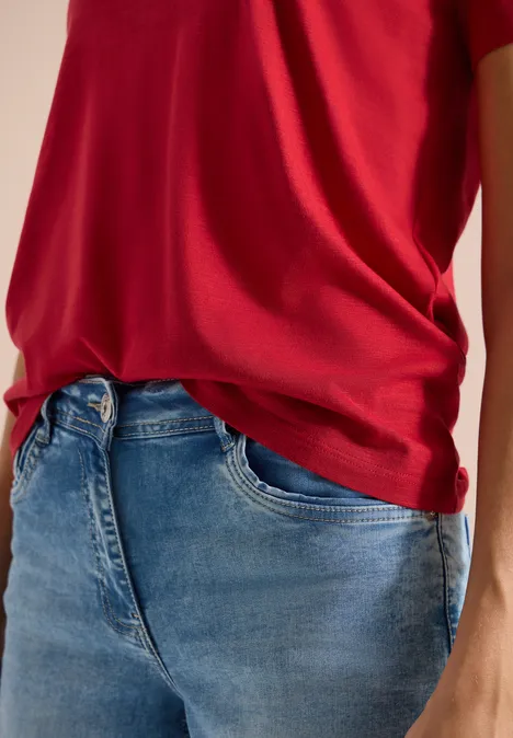 Basic T-Shirt mit Rundhals in Unifarbe tamarillo red Eine Person trägt rotes T-Shirt und blaue Jeans.