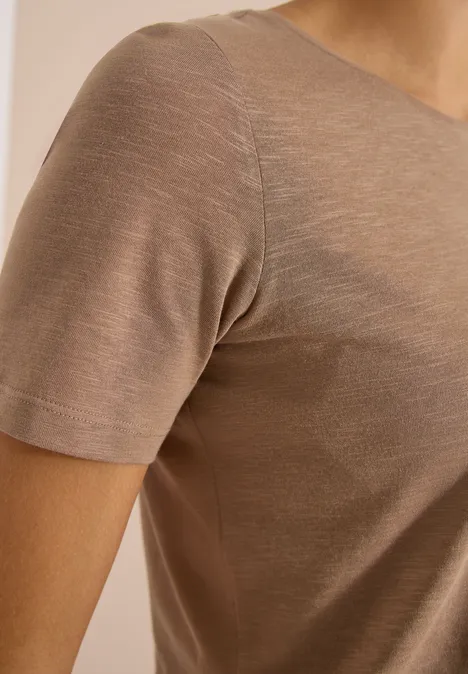 Basic T-Shirt mit Rundhals in Unifarbe creamy mocha Nahaufnahme einer Person in einem beige/braunen kurzärmligen, eng anliegenden Shirt aus weichem Stoff.