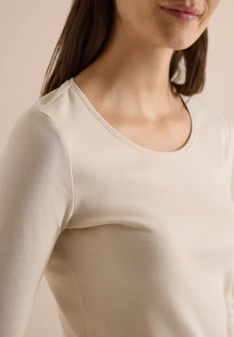 Basic Langarm Shirt mit Rundhals pearl beige Nahaufnahme einer Frau in cremefarbenem, eng anliegendem Langarmshirt vor neutralem Hintergrund.