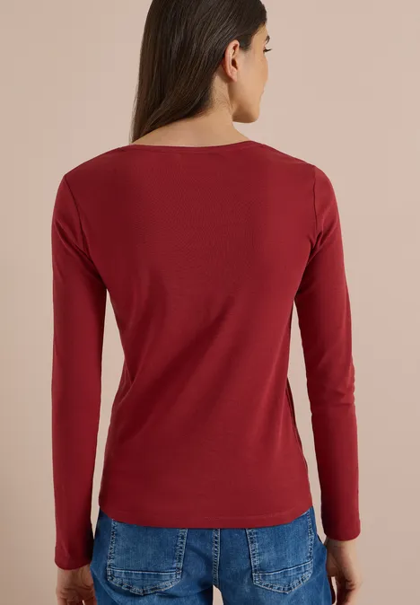 Frau von hinten in rotem Langarmshirt und blauen Jeans.