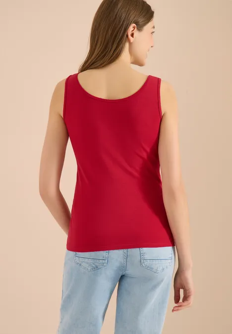 Femme vue de dos portant un débardeur rouge et un jean bleu clair.