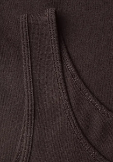 Nahaufnahme von zwei überlappenden, dunkelbraunen Baumwollshirts mit sichtbarer Naht
