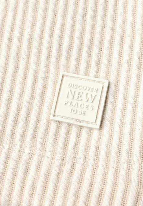 Beige ribstof met een vierkante patch met de tekst 'Discover New Places To Be'.