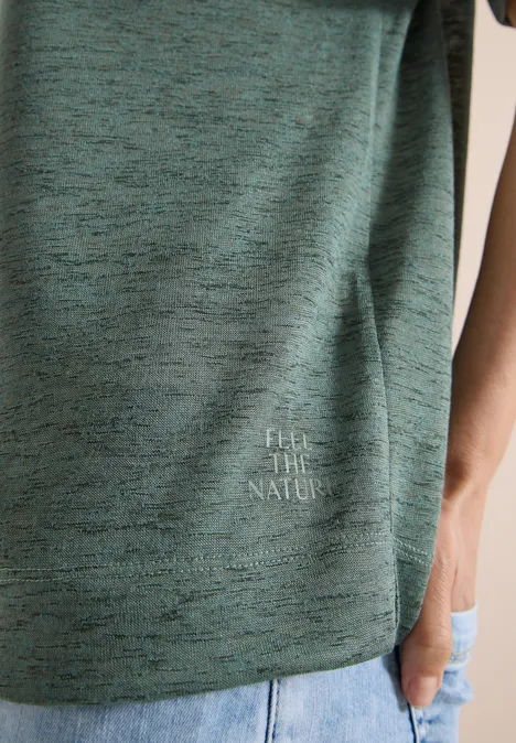 Gedeeltelijke weergave van een persoon in een groen gemêleerd t-shirt 'FEEL THE NATURE' met een spijkerbroek.