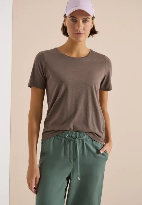 Basic T-Shirt mit Rundhals im 2er-Pack urban taupe/white Frau in grauem T-Shirt und grüner Hose vor hellem Hintergrund.