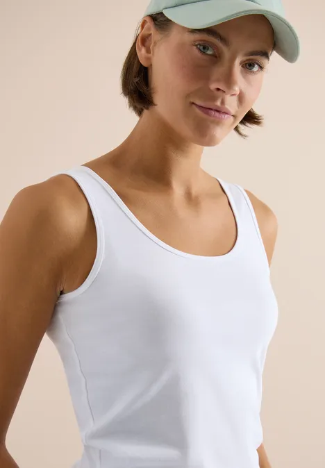 Basic Top mit Rundhals im 2er-Pack urban taupe/white Person mit weißem ärmellosem Top und Baseballcap vor neutralem, hellem Hintergrund.