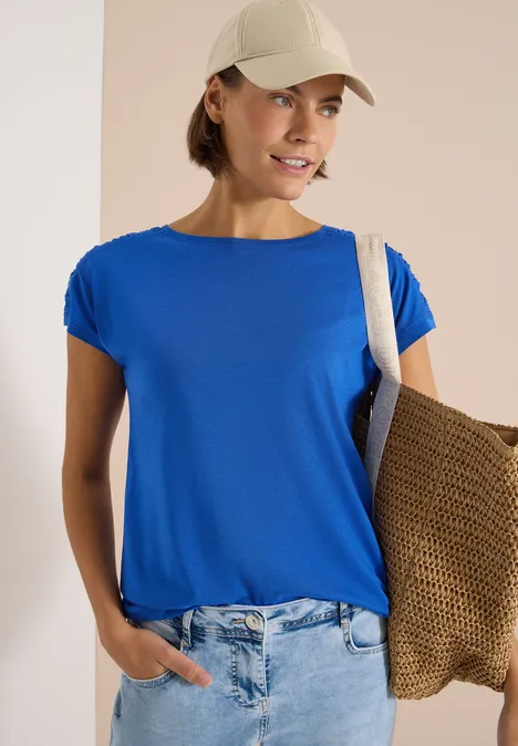 Kurzarm Shirt mit Boatneck und Raffung surf blue Person trägt blaues T-Shirt, Jeans, weiße Kappe und Strohtasche über der Schulter.