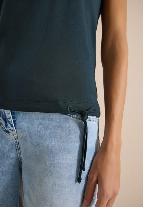 Kurzarm Shirt mit Boatneck und Raffung deep petrol blue Ein Torso in dunkelblauem Shirt mit seitlicher Kordel und hellblauen Jeans.