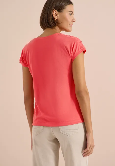 Kurzarm Shirt mit Boatneck und Raffung shiny coral Frau von hinten in korallfarbenem T-Shirt und beigefarbenen Hosen.