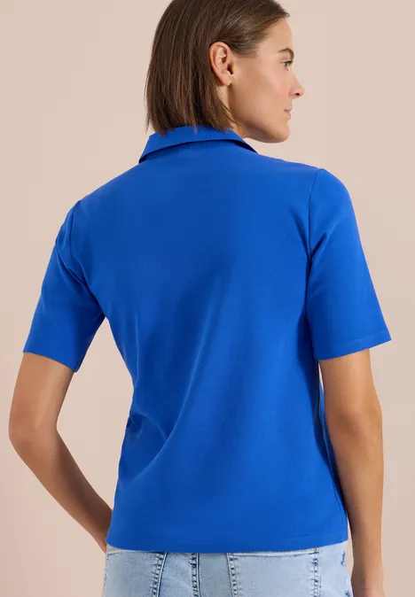 Frau von hinten in royalblauem kurzärmligen Polo-Shirt