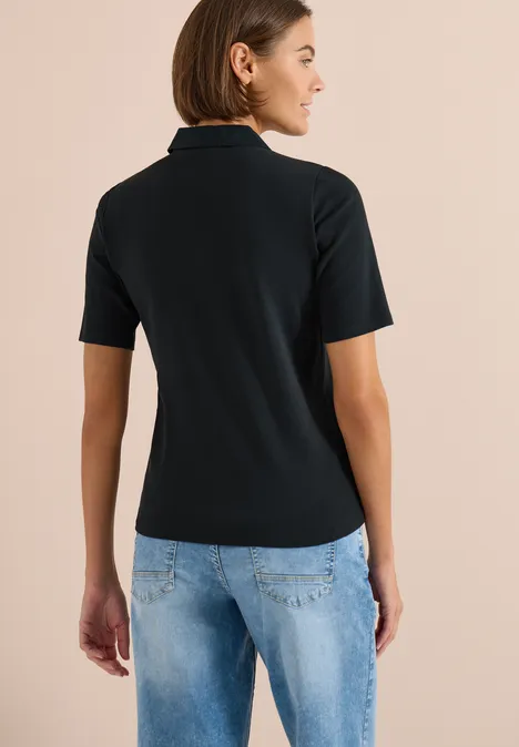 Basic Poloshirt mit Kurzarm palm breeze green Rückansicht einer Person in schwarzem Polo-Shirt und blauen Jeans vor neutralem Hintergrund