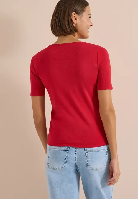 Rückansicht einer Person mit rotem T-Shirt und hellblauer Jeans.