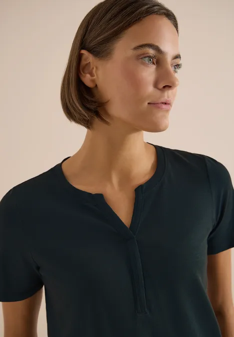 Basic Shirt im Tunika-Look deep petrol blue Oberkörper einer Person mit unscharfem Gesicht, kurzen Haaren und dunkelblauem Henley-Shirt vor hellem Hintergrund.