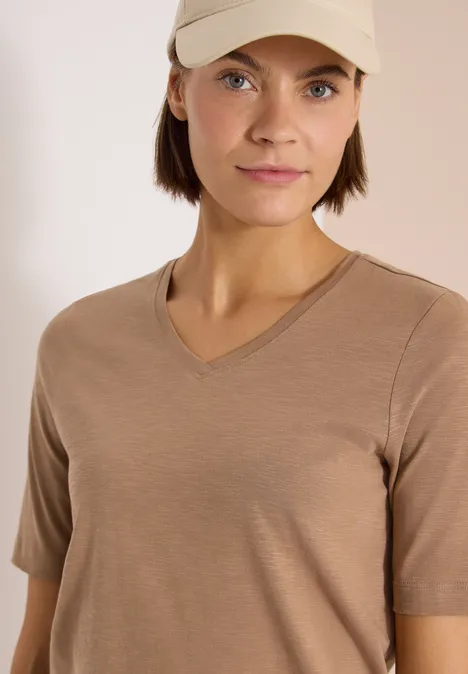 Basic T-Shirt mit Kurzarm und V-Neck creamy mocha Eine Person trägt ein schlichtes beigefarbenes T-Shirt mit V-Ausschnitt.