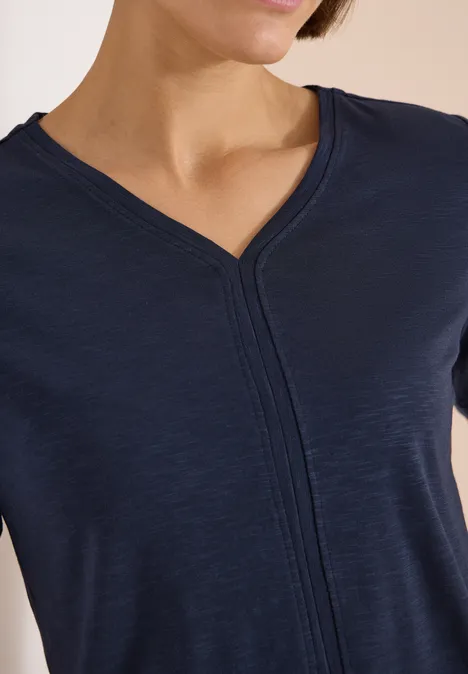 Kurzarm T-Shirt im Tunika-Look universal blue Eine Frau trägt ein dunkelblaues T-Shirt mit V-Ausschnitt und zentraler Naht.
