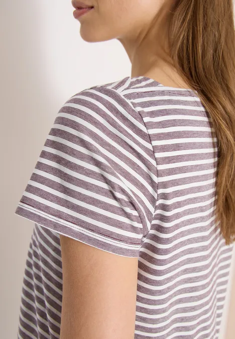 Zijaanzicht van een vrouw met bruin haar in een wit-paars gestreept T-shirt voor een witte achtergrond.