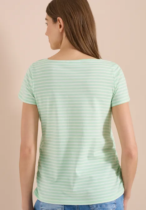 Femme de dos portant un t-shirt rayé vert menthe et blanc, cheveux bruns lâchés.