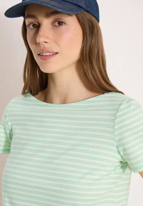 Une personne portant un t-shirt rayé turquoise-blanc et une casquette bleue foncée devant un fond clair.