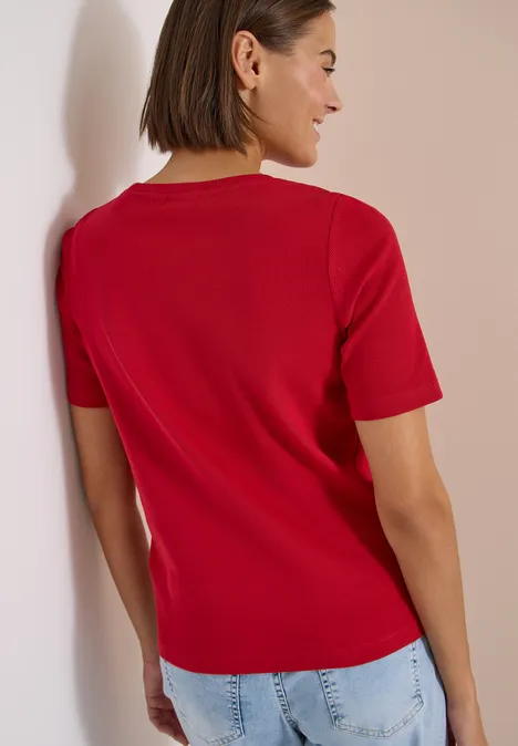 Basic T-Shirt in Rippstruktur tamarillo red Rückansicht einer Person in rotem Kurzarmshirt und hellblauen Jeans vor neutralem Hintergrund.