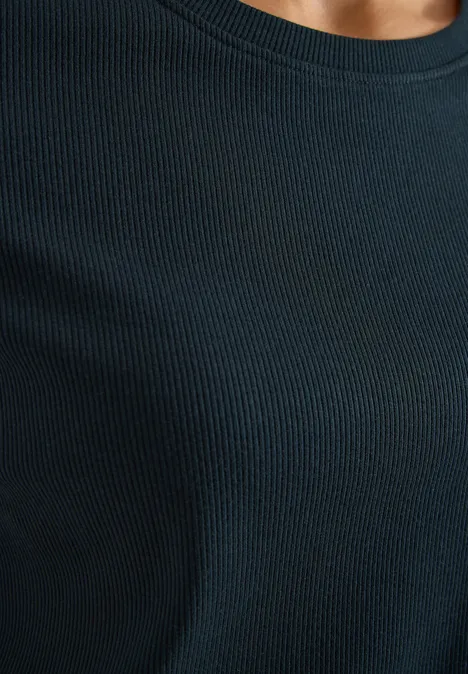 Basic T-Shirt in Rippstruktur deep petrol blue Eine Person trägt ein schwarzes, fein geripptes Oberteil, Blick nur auf den Oberkörper.