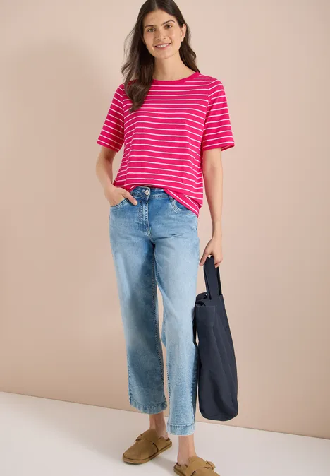 Persoon draagt rood-wit gestreept T-shirt, wijde blauwe spijkerbroek, olijfgroene loafers en een donkerblauwe tas.