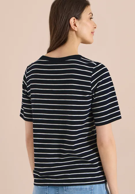 Rugaanzicht van een persoon in een zwart-wit gestreept T-shirt tegen een beige achtergrond.