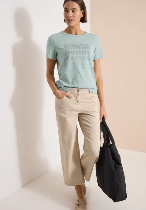 Kurzarm Shirt im Ausbrenner-Look crystal mint Frau trägt mintgrünes T-Shirt, helle weite Hosen und schwarzen Shopper vor hellem Hintergrund