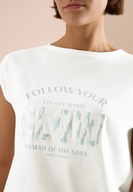 Vrouw draagt wit T-shirt met pastelopdruk en grafisch motief op de borst.