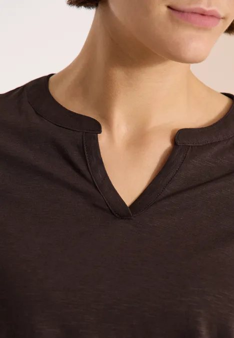 Nahaufnahme des Halses und des V-Ausschnitts eines dunkelbraunen Shirts.