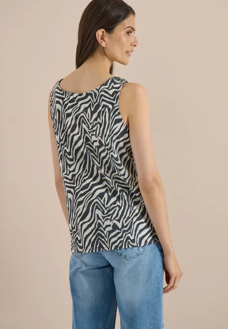 Haut à col rond et détails smockés palm breeze green Vue de dos d'une femme en jean bleu et débardeur sans manches à motif zèbre.