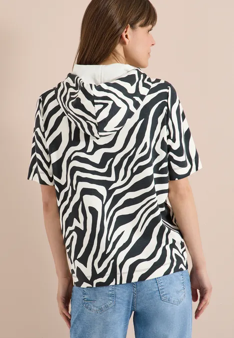 Frau von hinten in Zebra-Print-Kapuzenshirt mit kurzen Ärmeln und Jeans.