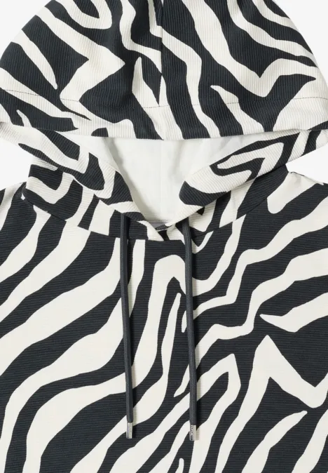 Weicher Kapuzenpullover in Zebramuster (schwarz-weiß) mit Kordelzug.