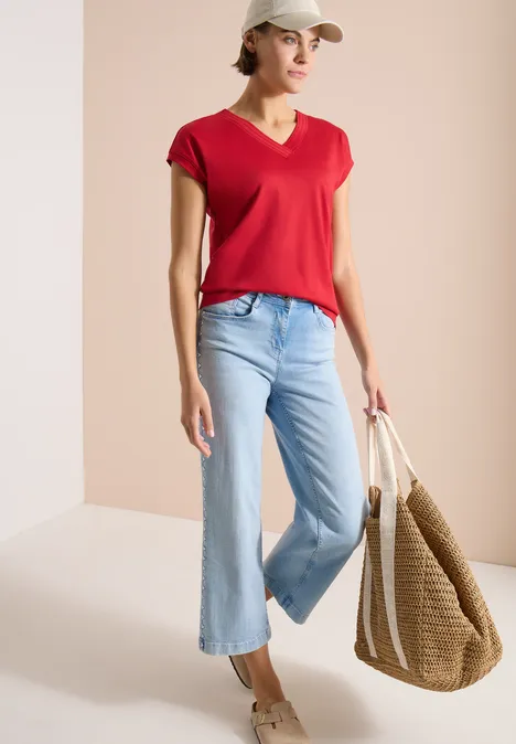 T-shirt à manches courtes et col en V en couleur unie tamarillo red Femme porte un t-shirt rouge, un jean large bleu et un grand sac en paille.