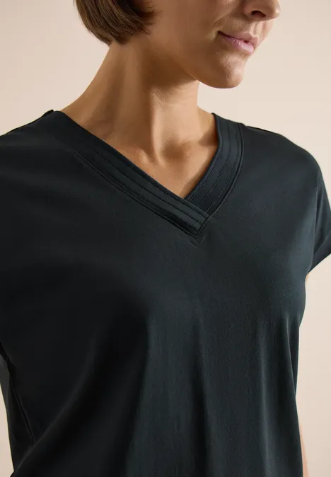 Frau trägt ein schwarzes T-Shirt mit V-Ausschnitt