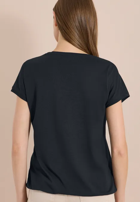 Rückansicht einer Person mit schwarzem T-Shirt vor hellem Hintergrund.