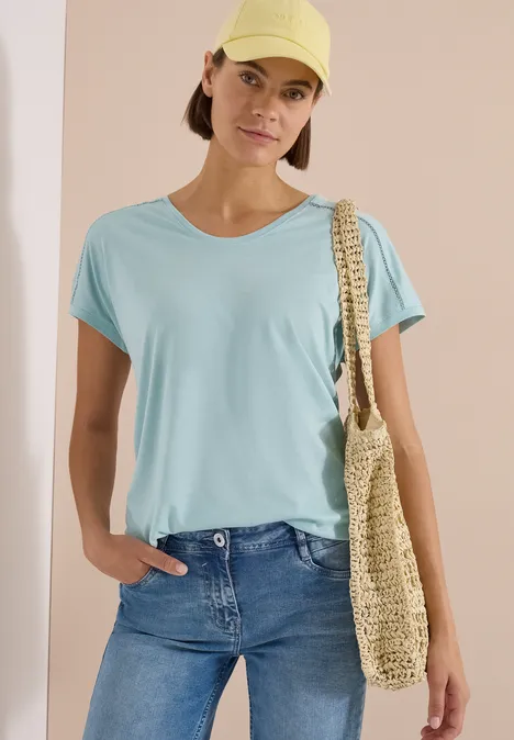 T-Shirt mit V-Neck und Spitzendetail crystal mint Eine Frau trägt ein hellblaues T-Shirt, Jeans und eine Strohtasche.