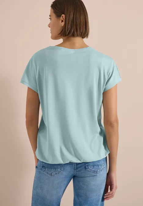 T-Shirt mit V-Neck und Spitzendetail crystal mint Frau von hinten in lockerem hellblauen T-Shirt und Jeans.