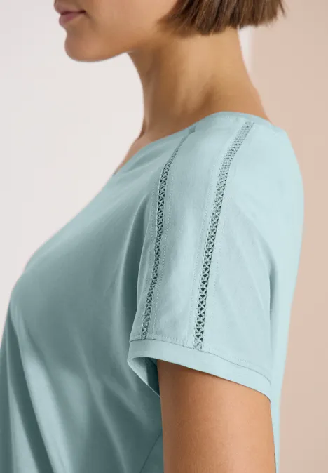 T-Shirt mit V-Neck und Spitzendetail crystal mint Seitliches Profil einer Frau in pastellgrünem T-Shirt mit Zierstreifen, vor hellem Hintergrund.