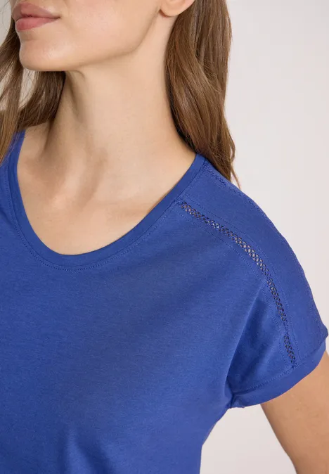 Shirt met V-hals en kanten detail deep river blue Close-up van een vrouw in een blauw t-shirt, bovenlichaam tot de kin zichtbaar.