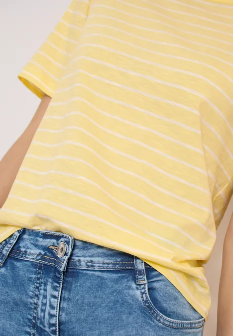 T-shirt jaune à rayures blanches, enfilé décontracté dans un jean bleu taille haute.